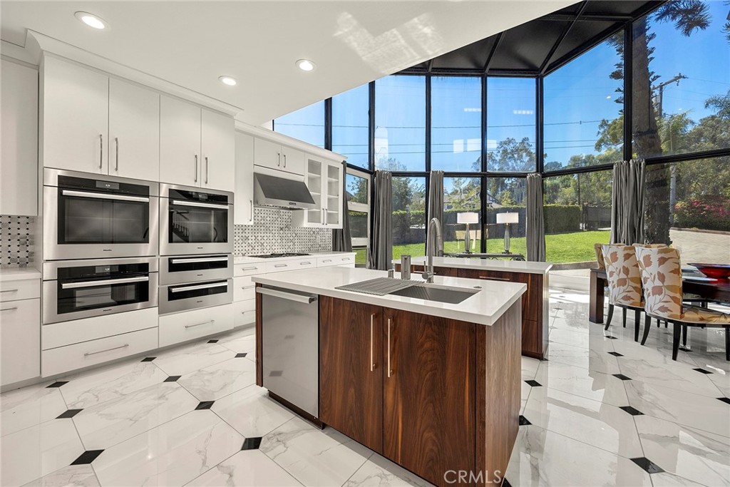 Modern kitchen with a dark wood island and floor-to-ceiling windows overlooking a green yard.
