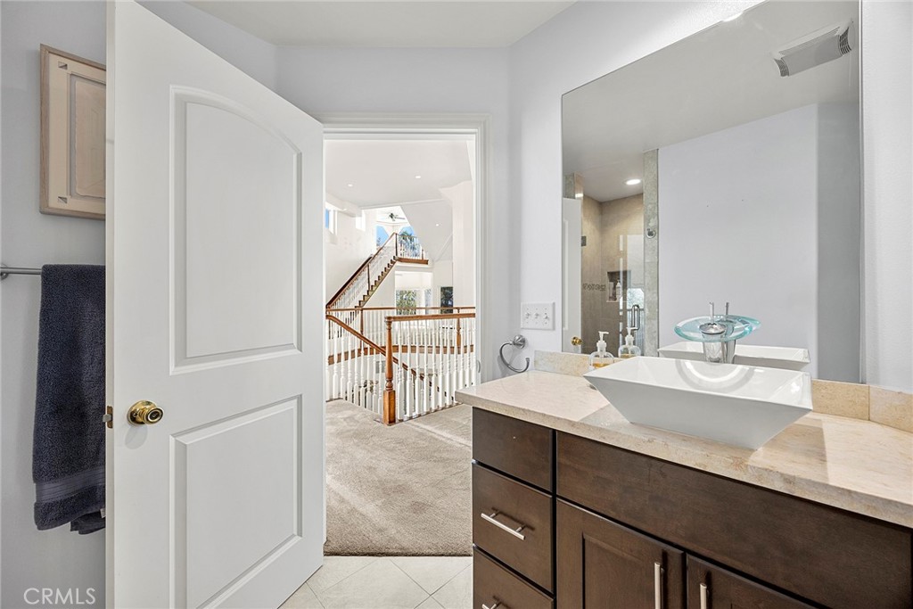 Bathroom with a white vessel sink and dark wood vanity, looking through an open doorway toward a staircase.