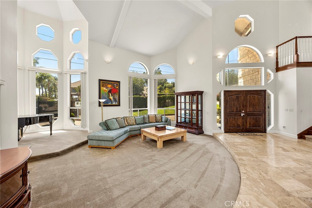 Living room with a curved sectional, vaulted ceiling, tall windows, and a dark wood double front door.