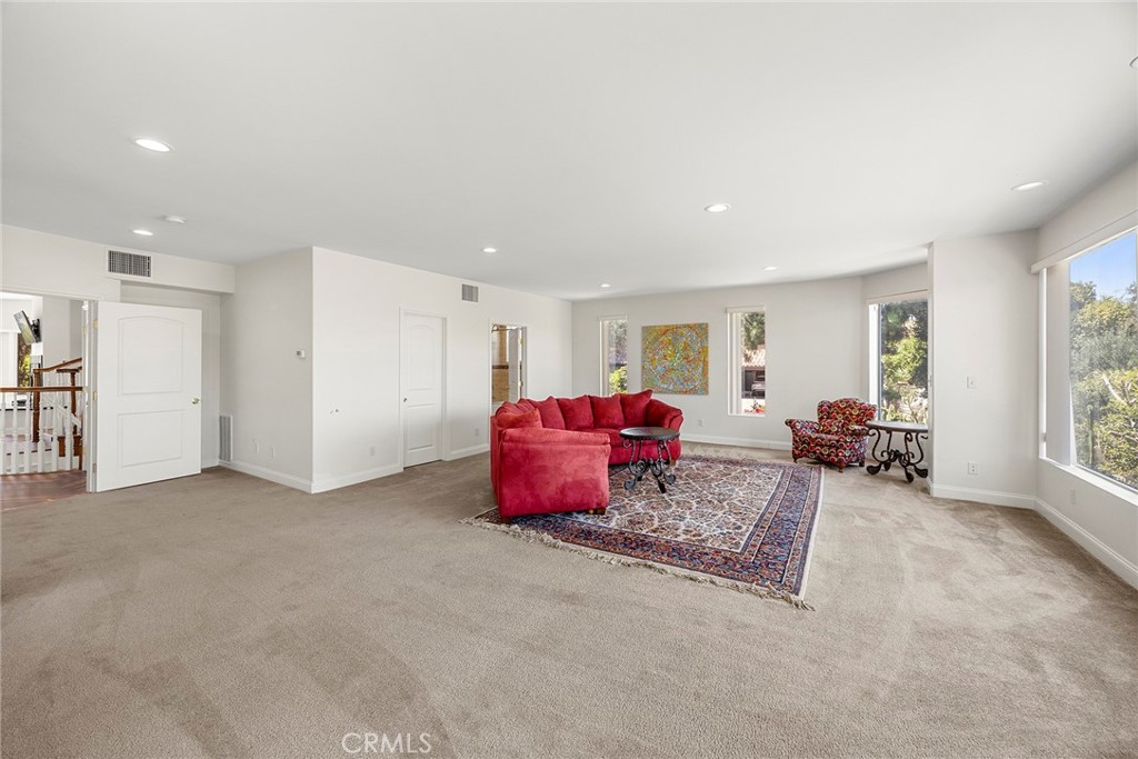 Spacious living room with red sofas, an ornate rug, and large garden-facing windows.