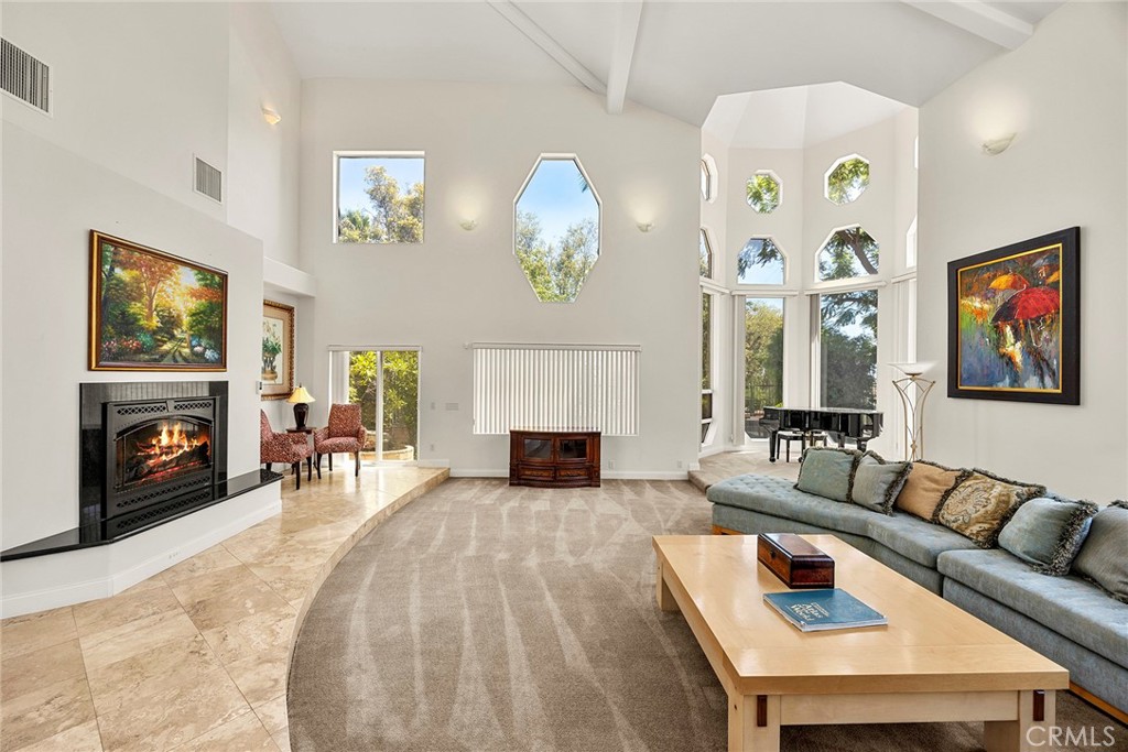 Living room with a fireplace, vaulted ceilings, tall windows, and a gray sectional sofa.