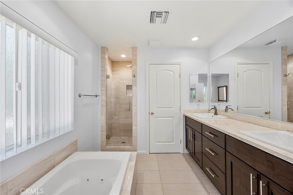 Primary bathroom with a soaking tub, tiled walk-in shower, and long double vanity.