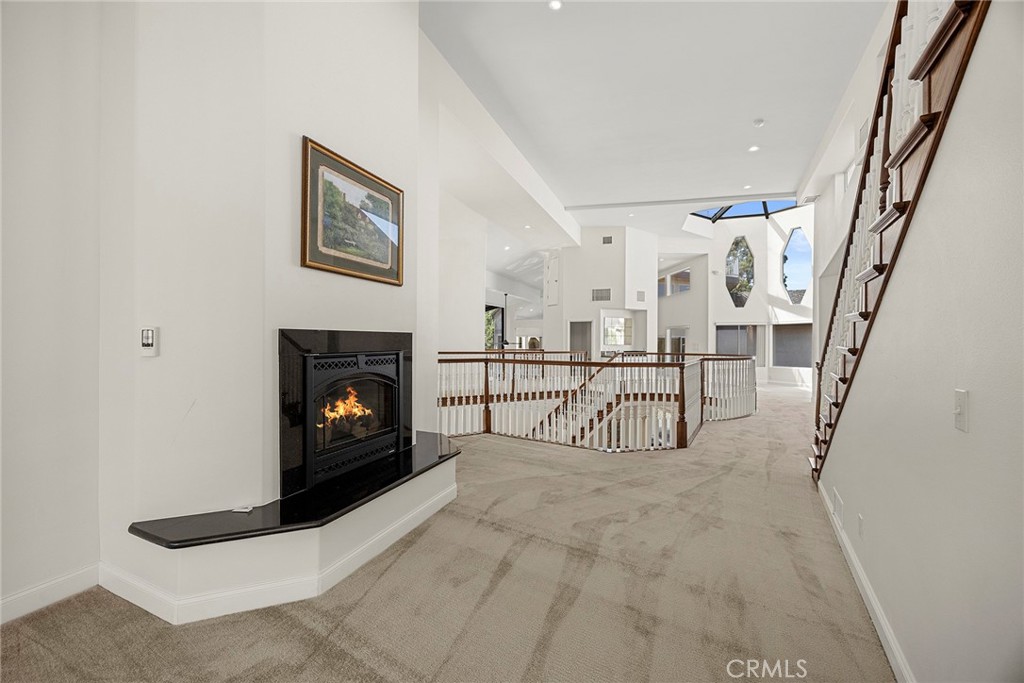 Upper-level landing with a fireplace, open stairwell, dark wood railings, skylights, and geometric windows.