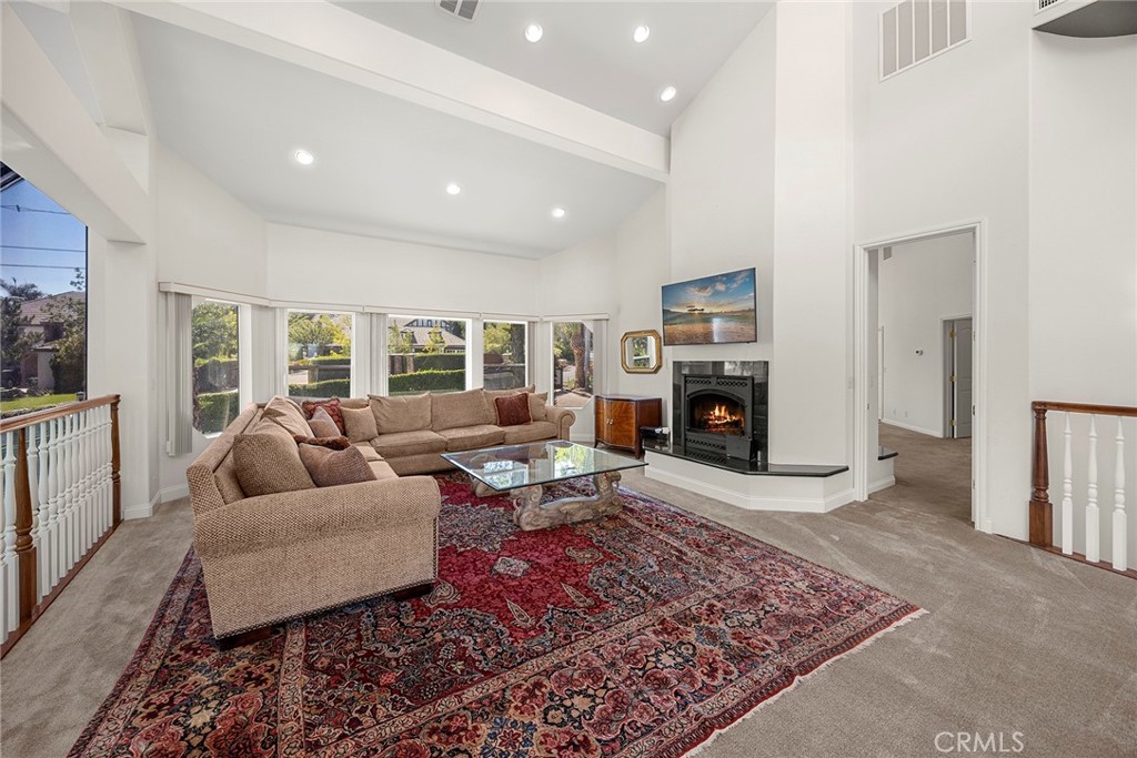 Living room with a beige sectional, patterned rug, fireplace, and vaulted ceiling.