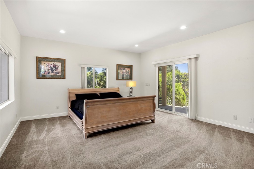 Bedroom with a wooden sleigh bed and sliding glass doors overlooking greenery.