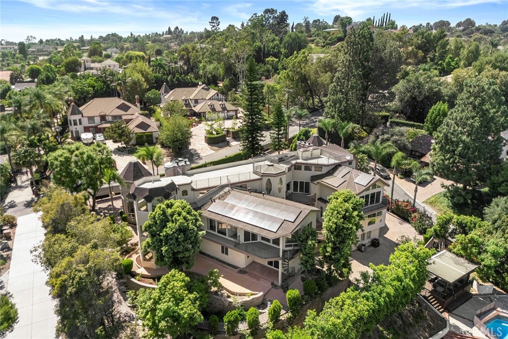 Aerial view of a large multi-level home with balconies and terraces among mature trees.