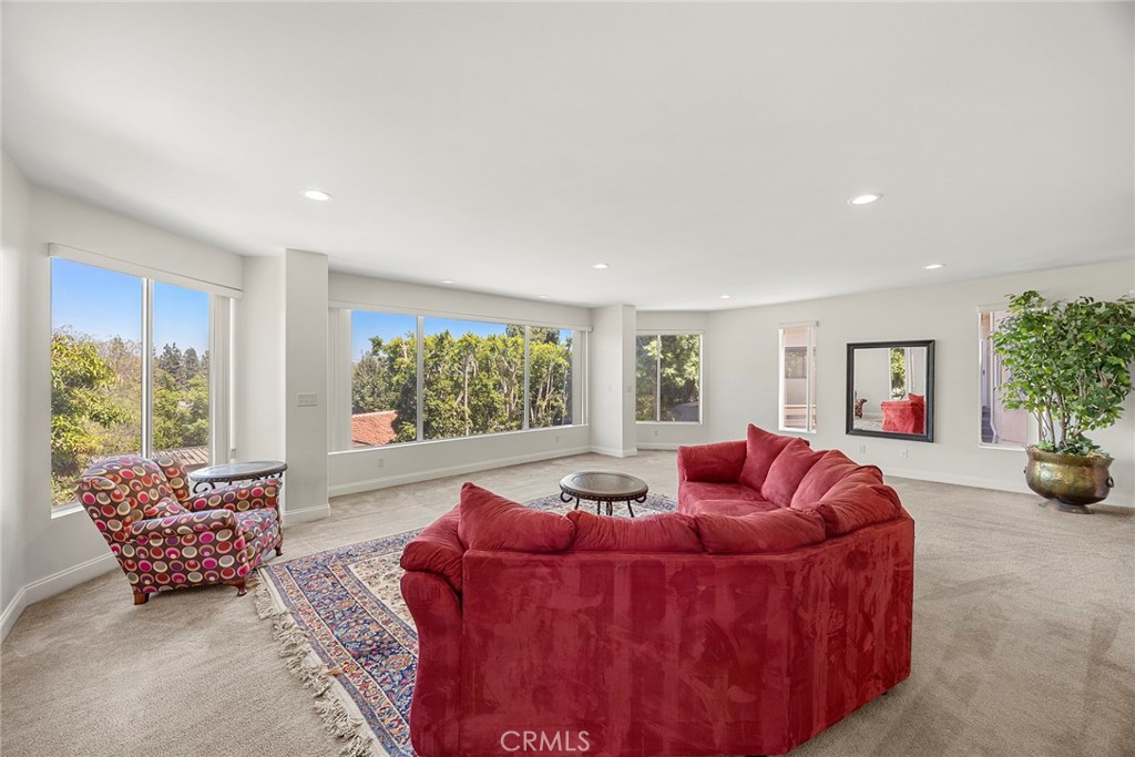 Living room with a red curved sectional and broad windows overlooking trees.