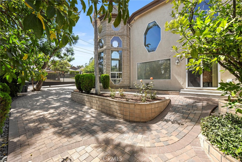 Home exterior with a curved paver courtyard, raised planter, and distinctive octagonal windows.