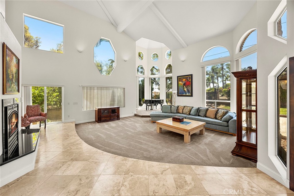Living room with vaulted ceilings, tall windows, a fireplace, and a gray sectional sofa.