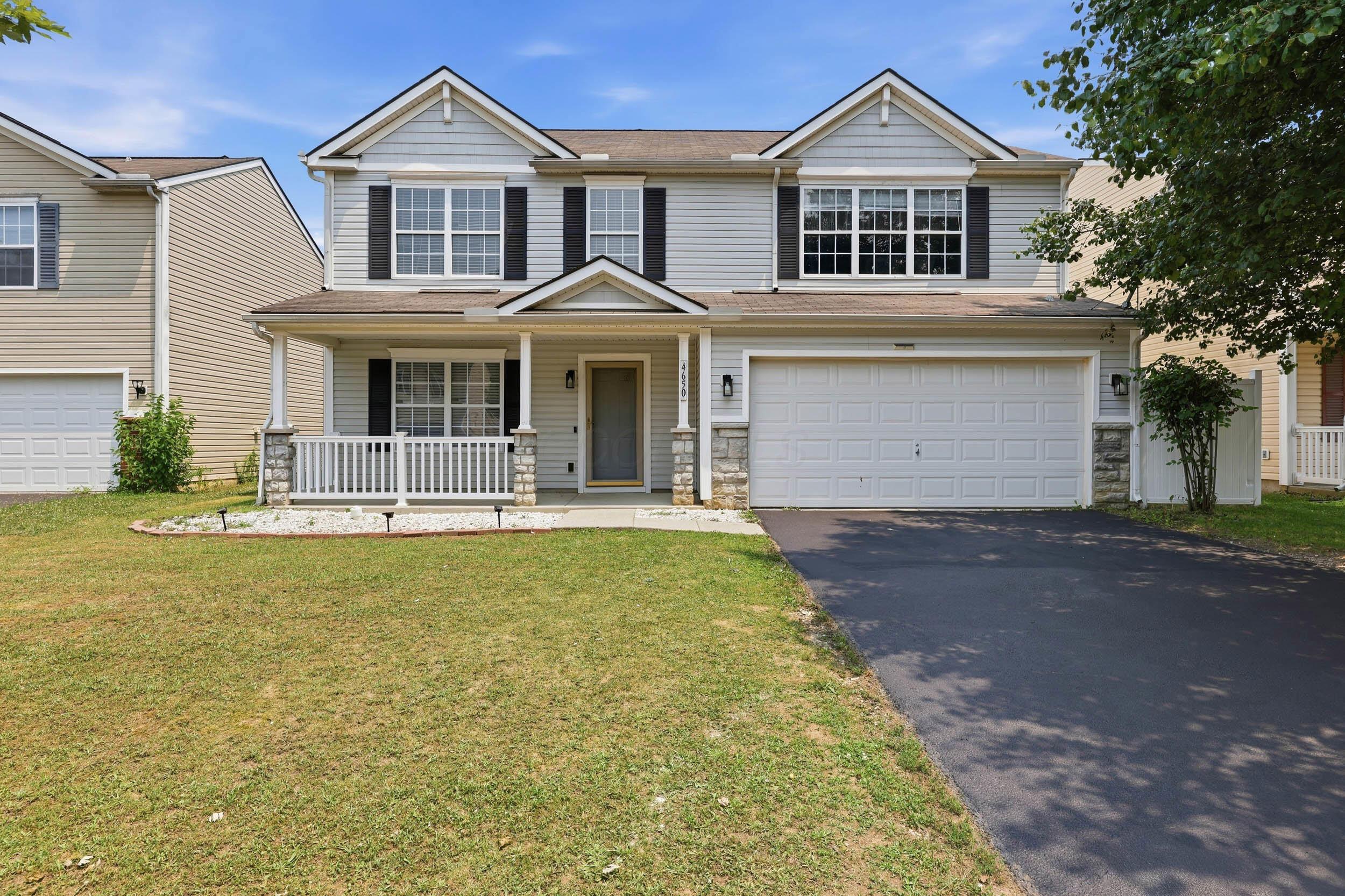 Two-story gray home with a covered porch, black shutters, and an attached two-car garage.