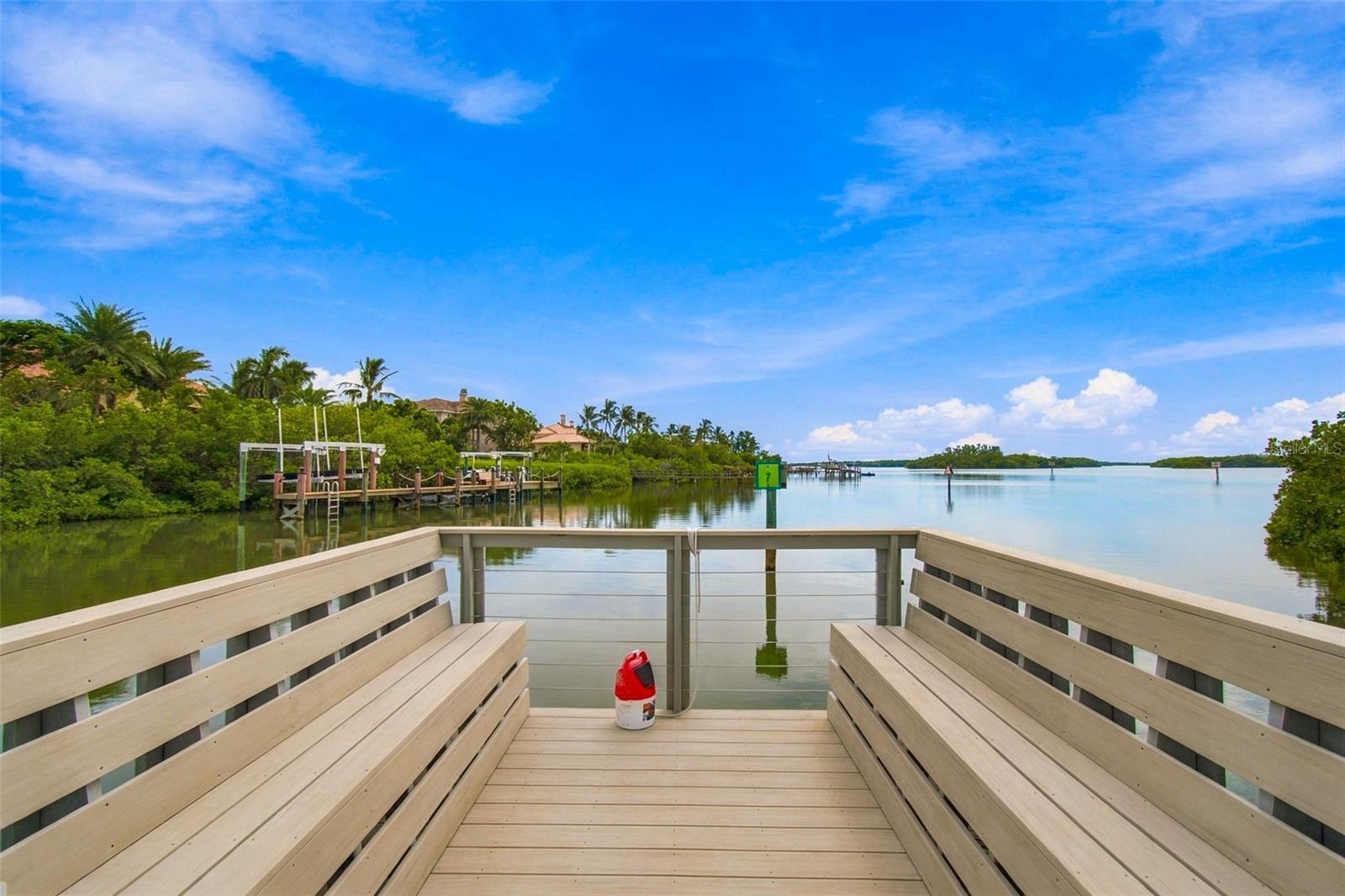 Waterfront dock with built-in benches overlooking calm water and mangrove-lined shores.