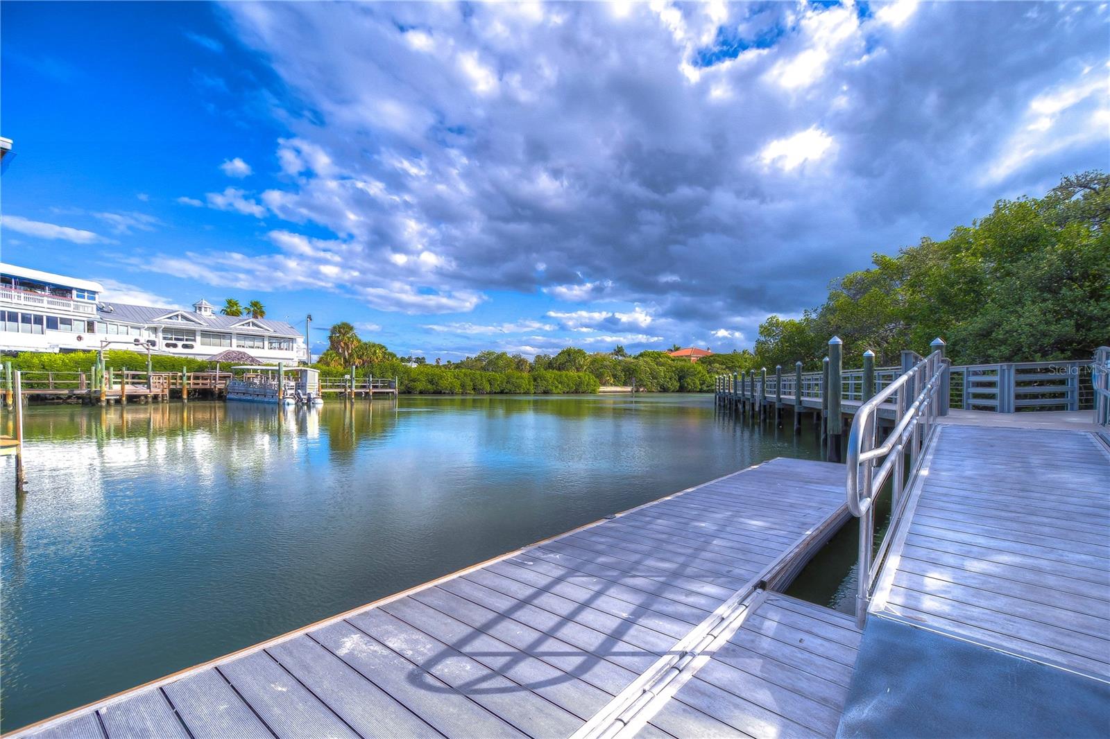 Waterfront dock and boardwalk extending over calm water beneath a cloudy sky