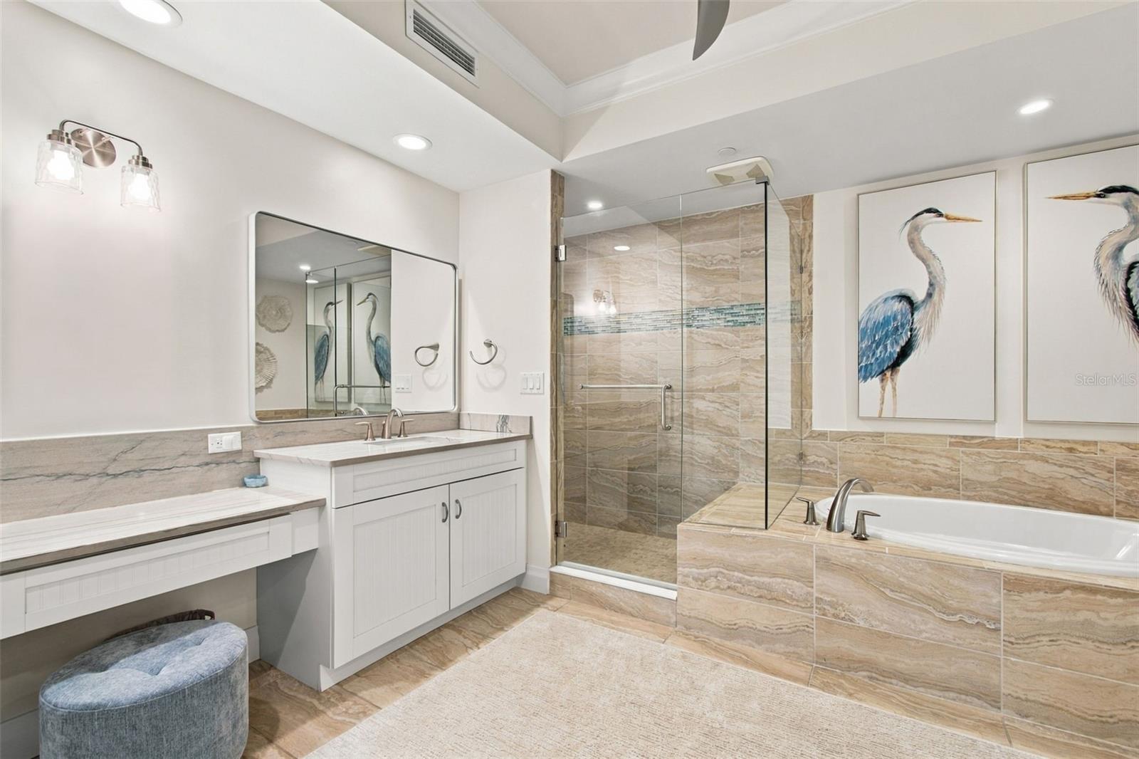 Bathroom with a glass shower, built-in tub, double vanity, and heron artwork.
