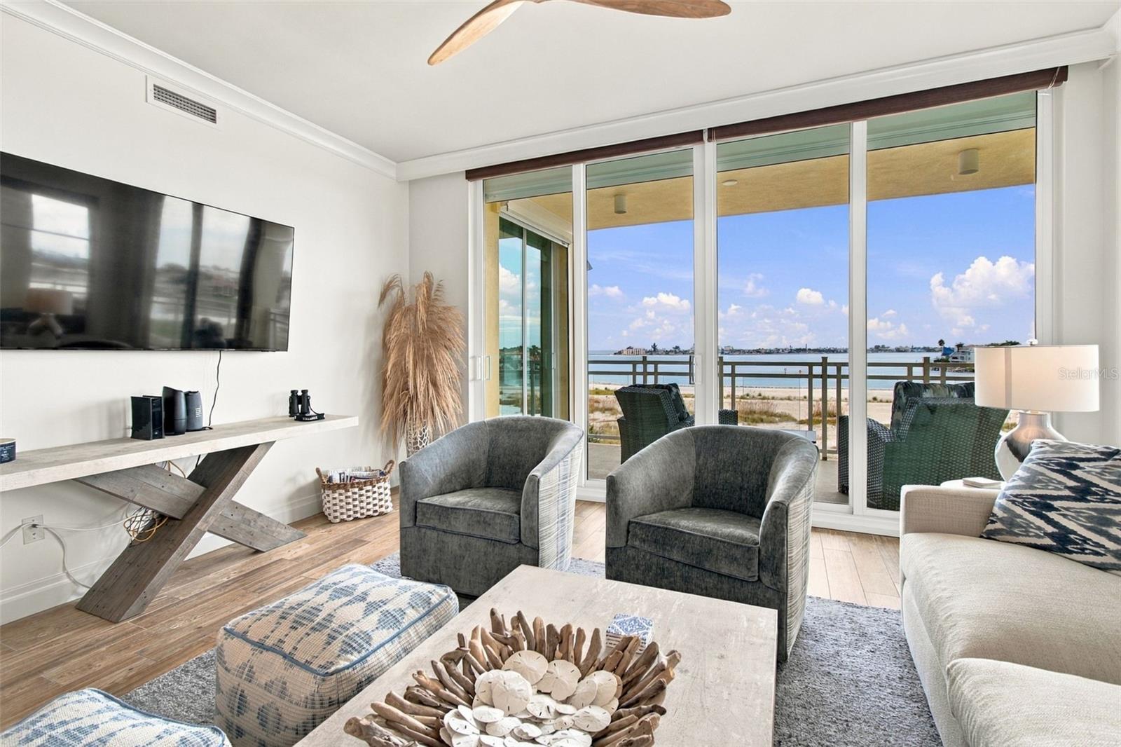 Living room with gray armchairs and sliding doors opening to a water view.