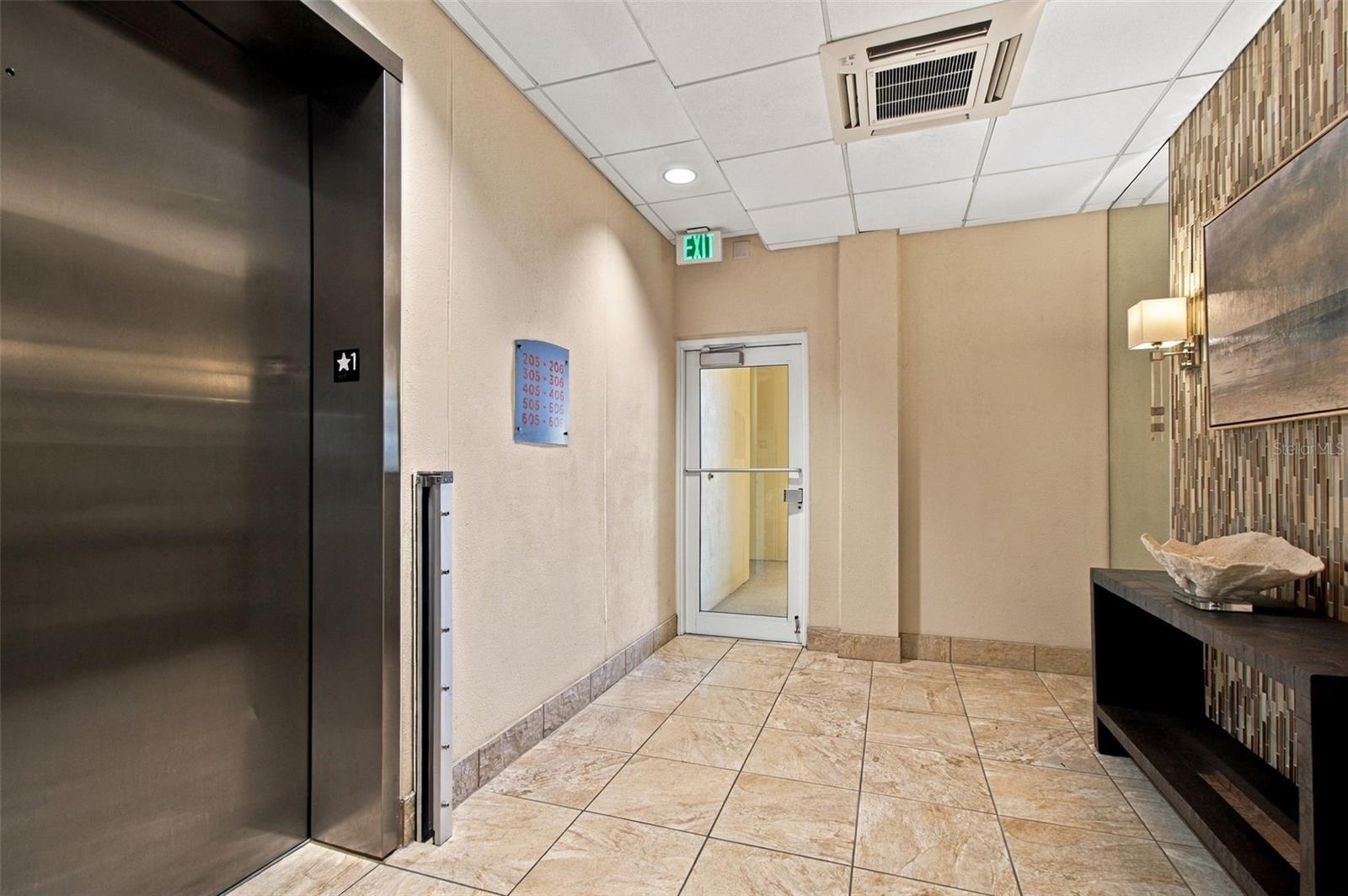 Condominium elevator lobby with stainless steel elevator doors and a tiled floor.