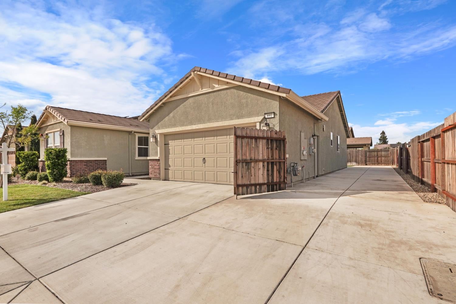 Home exterior with a broad driveway, attached garage, and fenced side access.