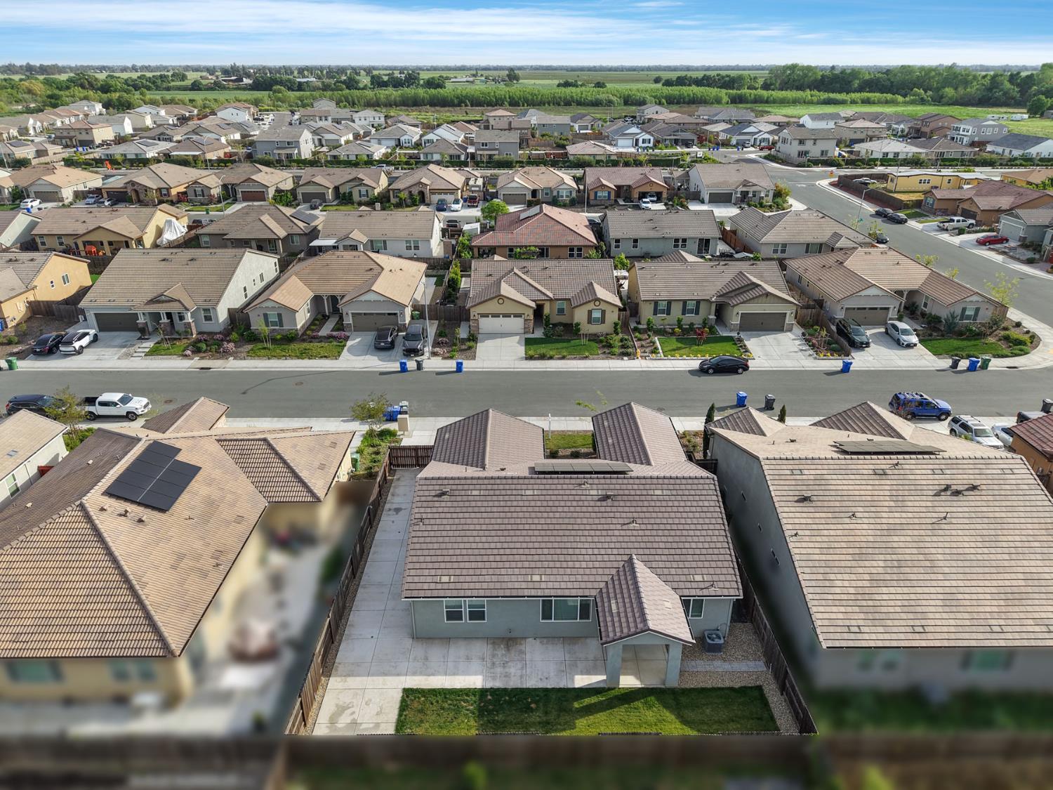 Aerial view of a suburban home with a fenced backyard, driveway, and surrounding neighborhood.
