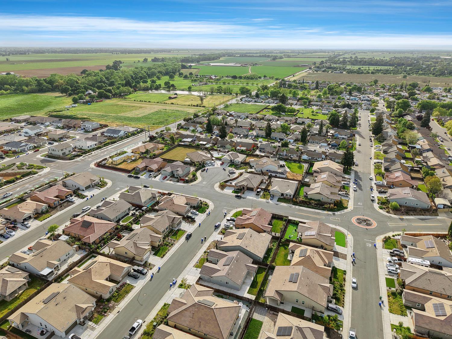 Aerial view of a neighborhood with cul-de-sacs and green fields beyond the homes.