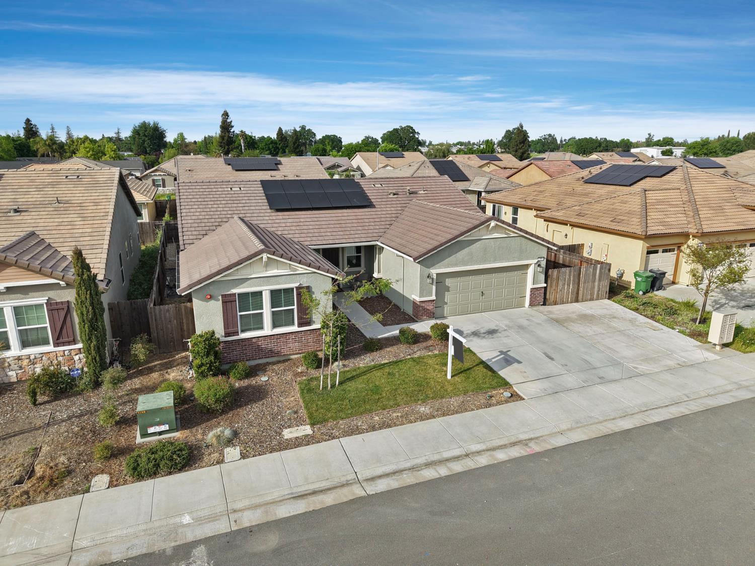 Aerial view of a gray stucco home with rooftop solar panels and an attached garage.