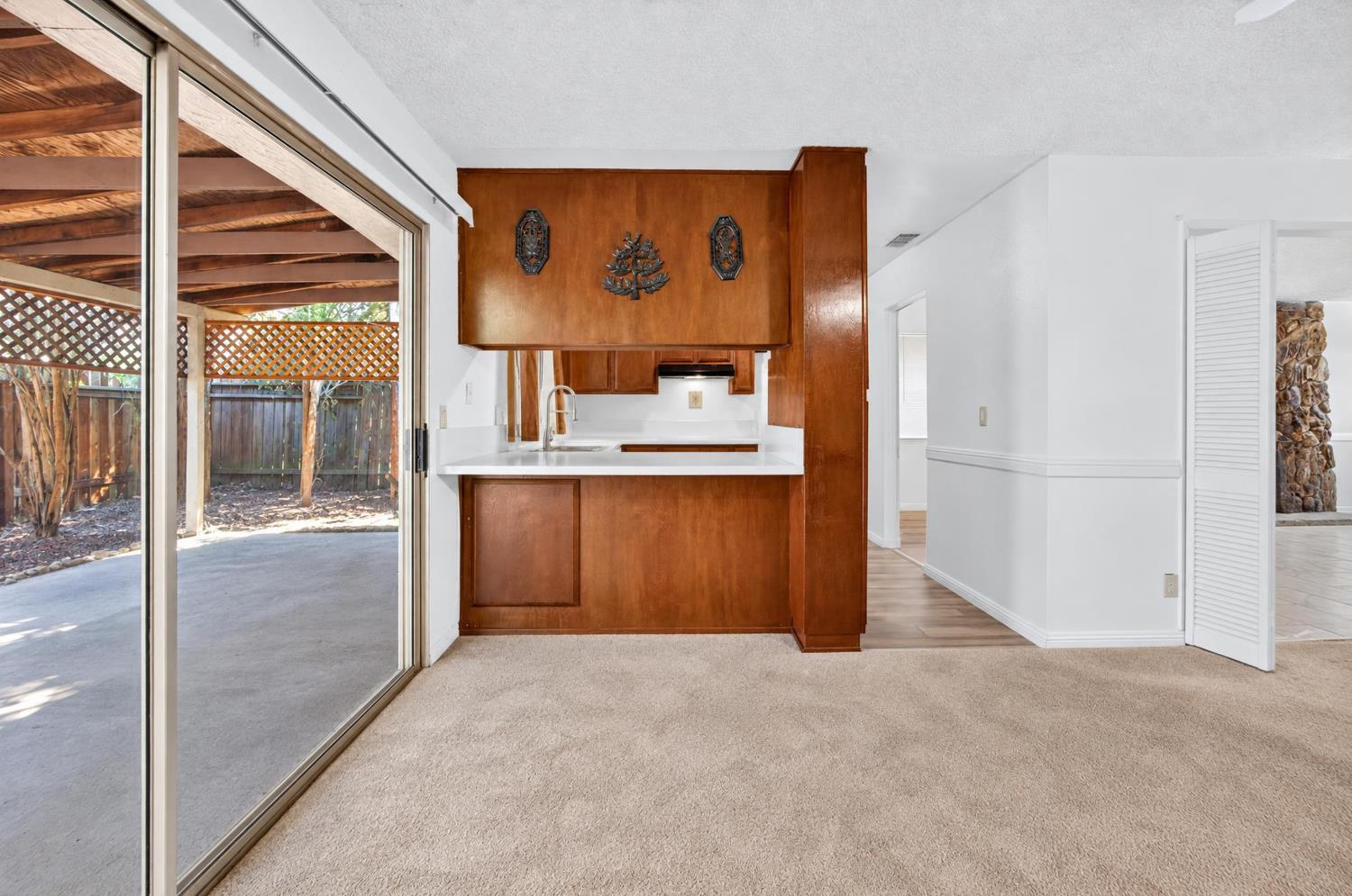 Kitchen with warm wood cabinetry and white counter beside a sliding door to a covered patio.