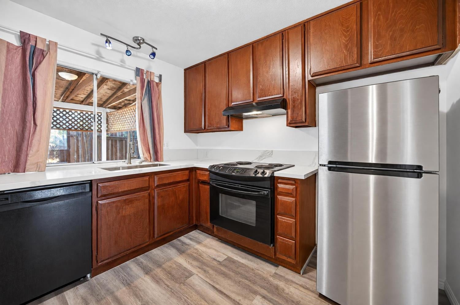 Kitchen with wood cabinets, stainless steel refrigerator, and window overlooking a covered patio.
