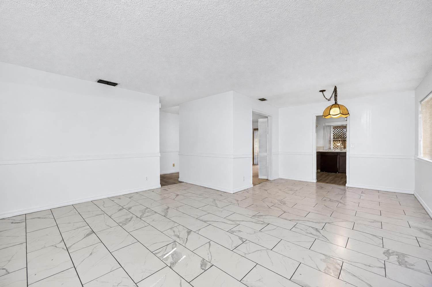 Empty dining area with marble-look tile flooring and a pendant light.