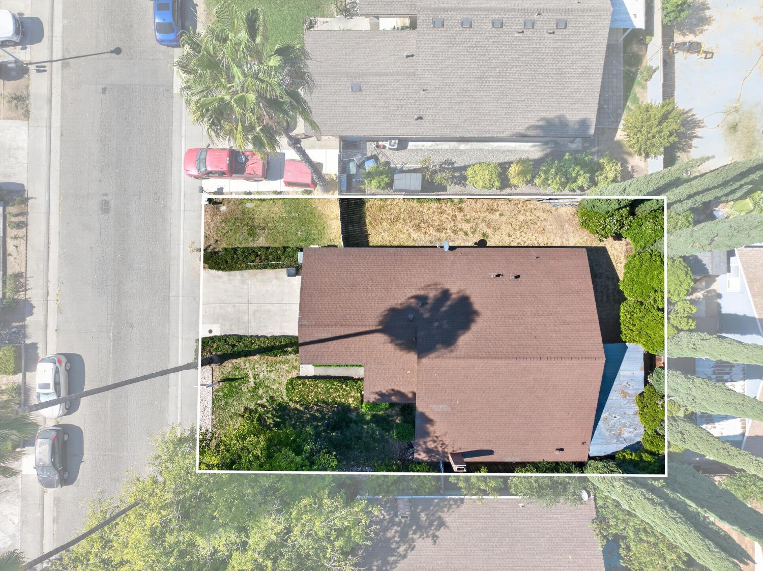 Aerial view of a home and lot outlined in white, with driveway and yard.