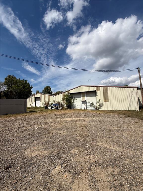 Metal commercial building beside a broad gravel lot under a partly cloudy sky.
