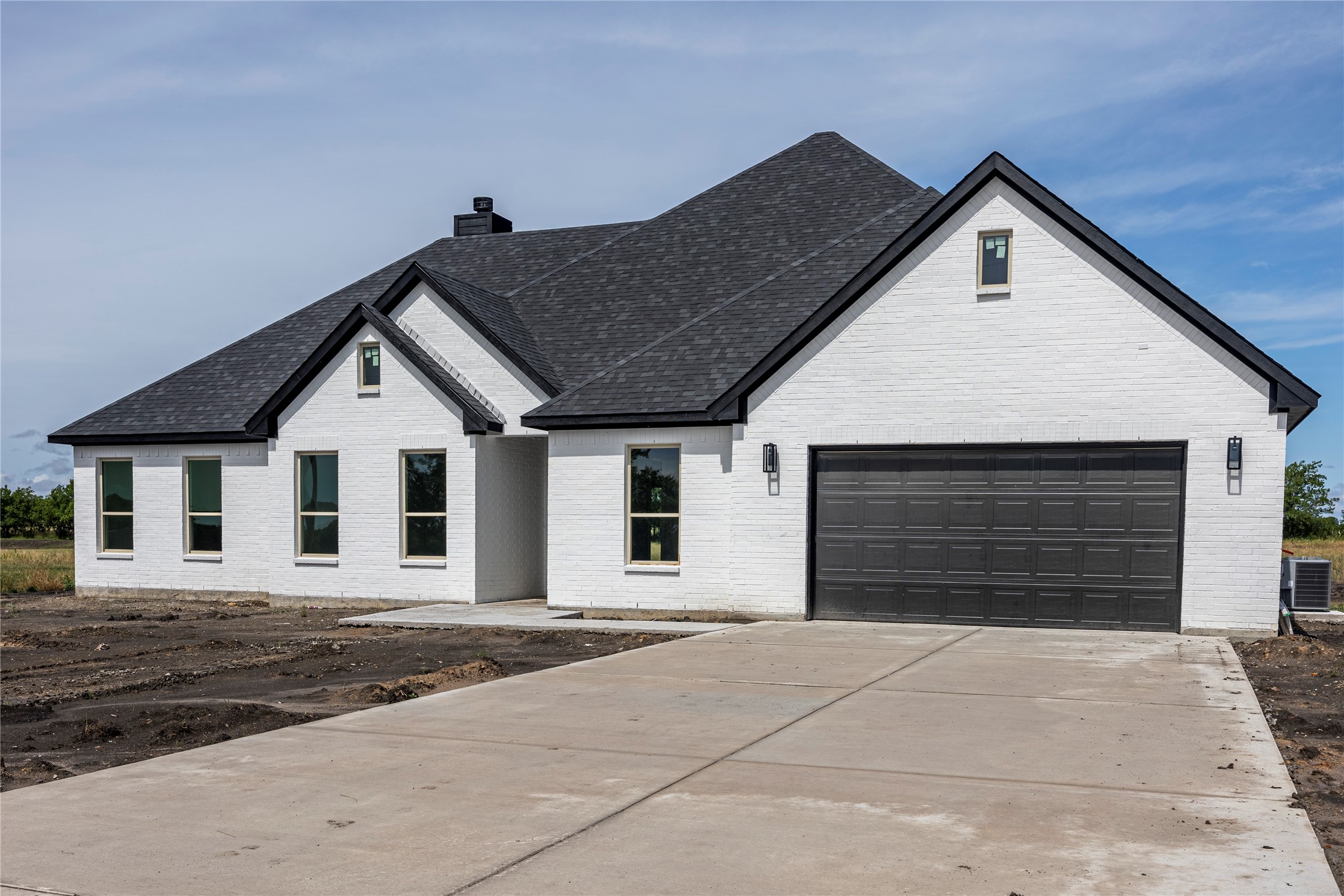 White brick house with a dark gabled roof, double garage, and wide concrete driveway.