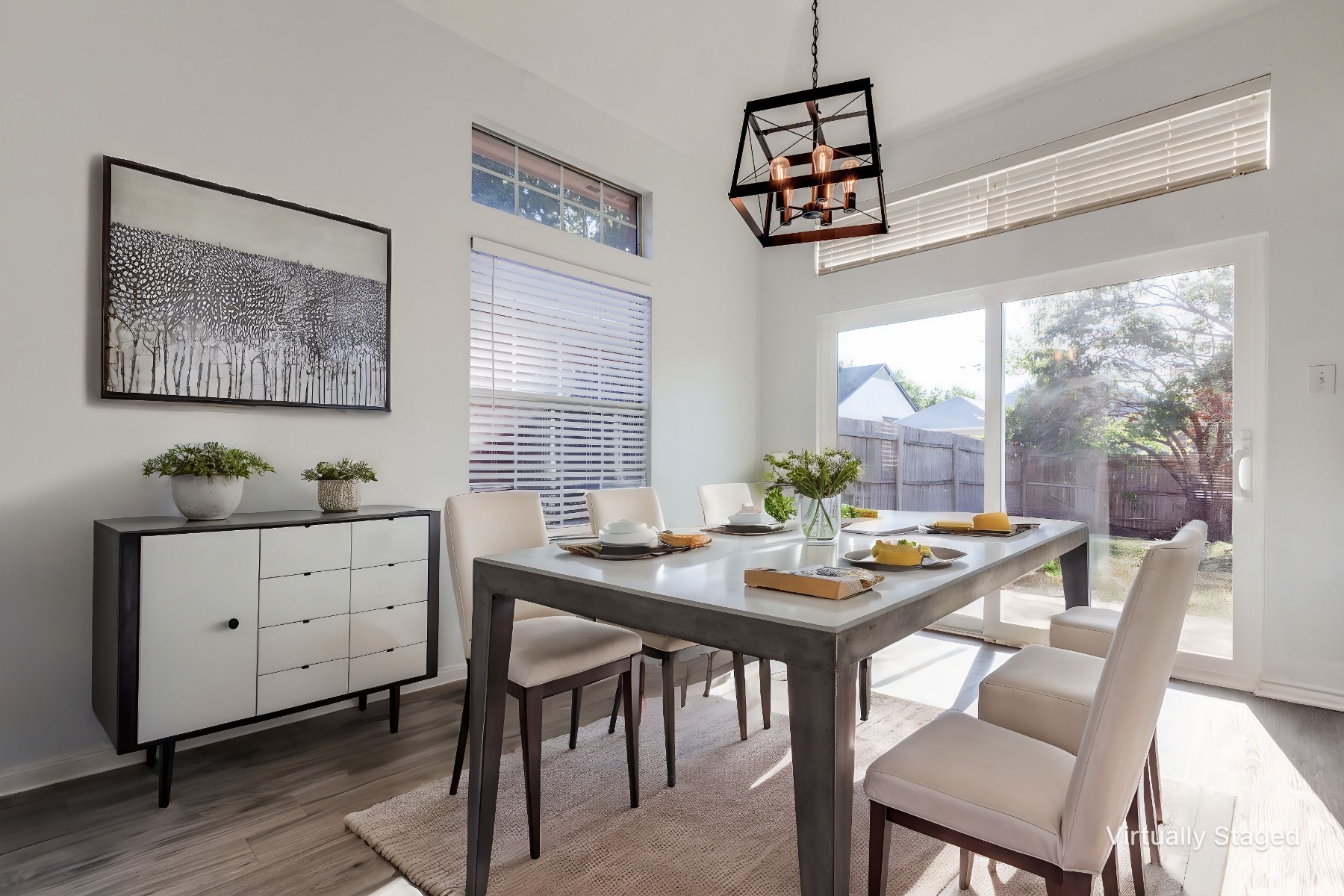 Virtually staged dining room with a long table, geometric pendant light, and sliding glass doors to the backyard.