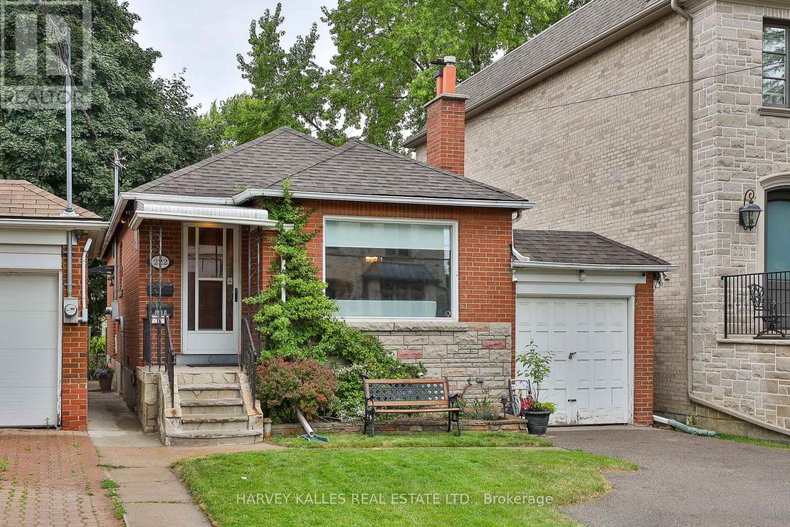 Red-brick bungalow with front steps, a white garage door, and a landscaped lawn.