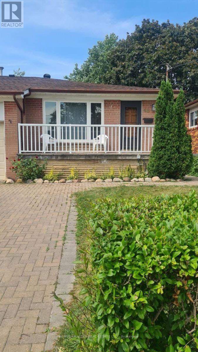 Brick house with a raised white-railed porch, paved walkway, and landscaped shrubs.