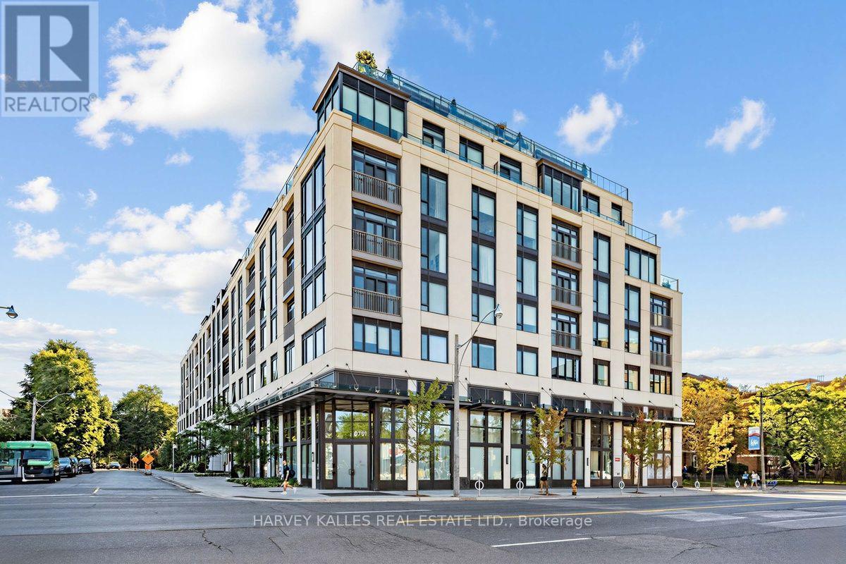 Modern multi-storey condominium building on a tree-lined corner, with balconies and glass-fronted ground-floor spaces.