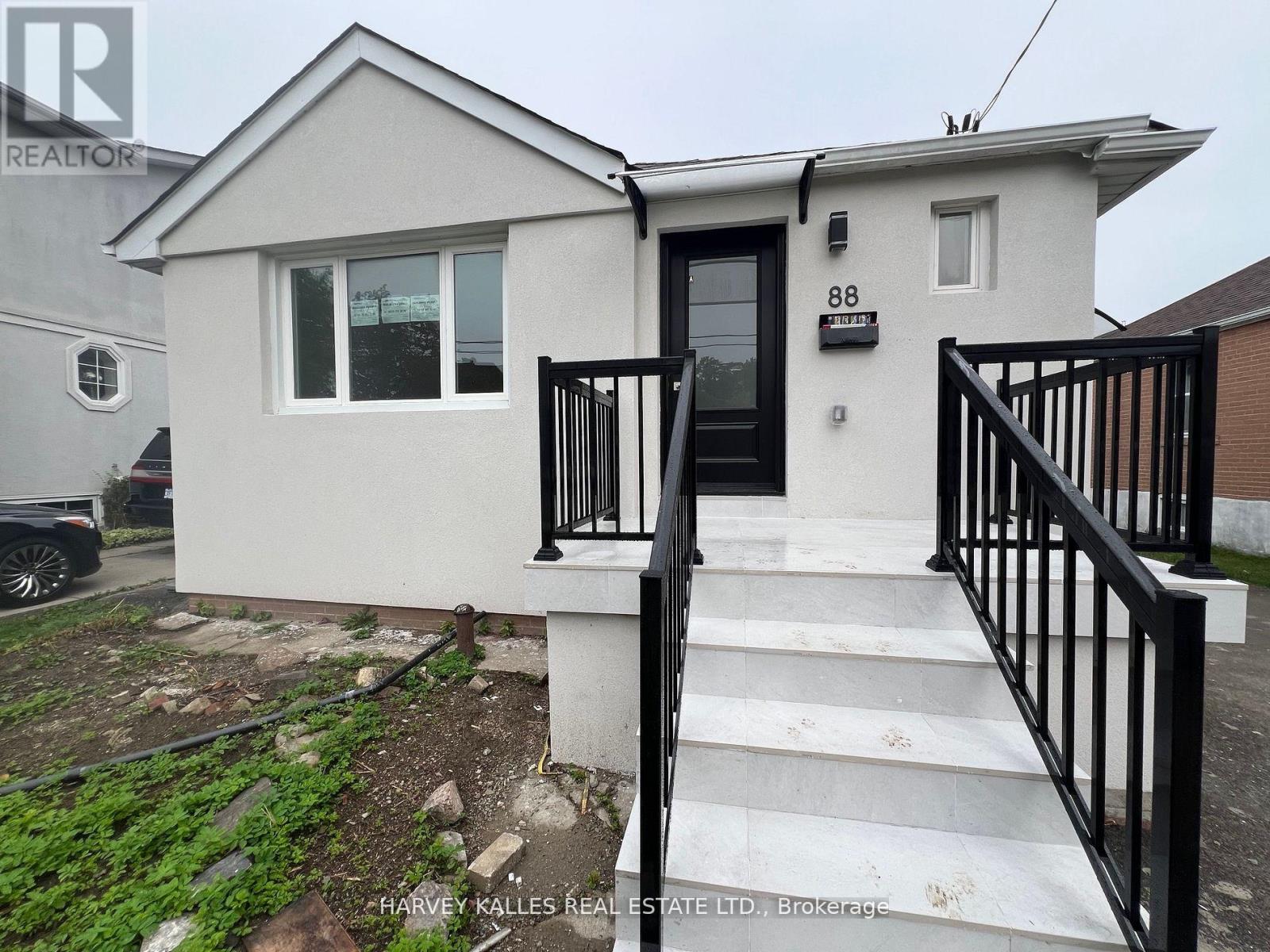 White single-story house with black entry railings and broad tiled front steps.