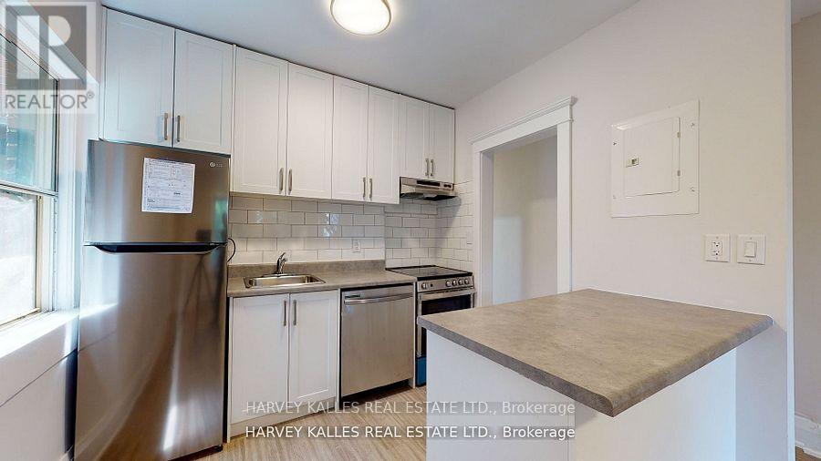 Kitchen with white cabinets, stainless steel appliances, subway-tile backsplash, and a gray peninsula counter.