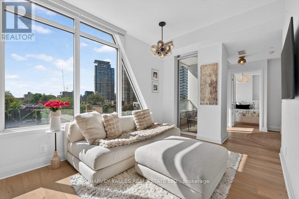 Bright condo living room with a white sectional, large windows, and city skyline views.