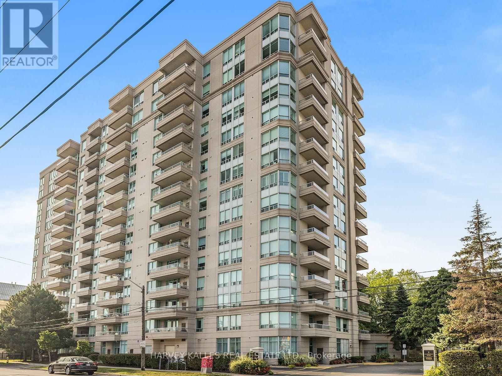 Beige condominium tower with glass balconies and a curved windowed corner, viewed from the street.