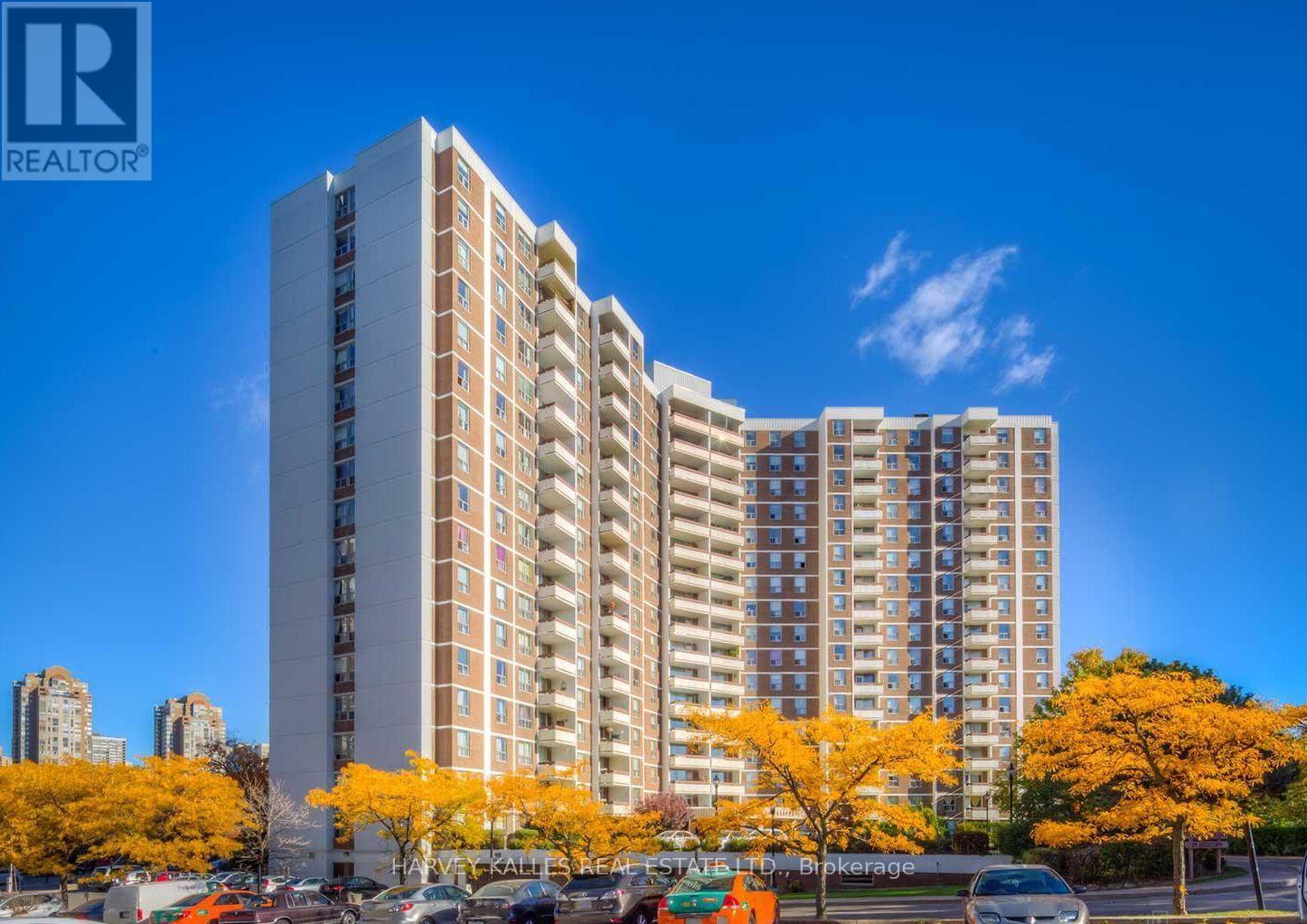 Apartment building with balconies and autumn trees along the street.