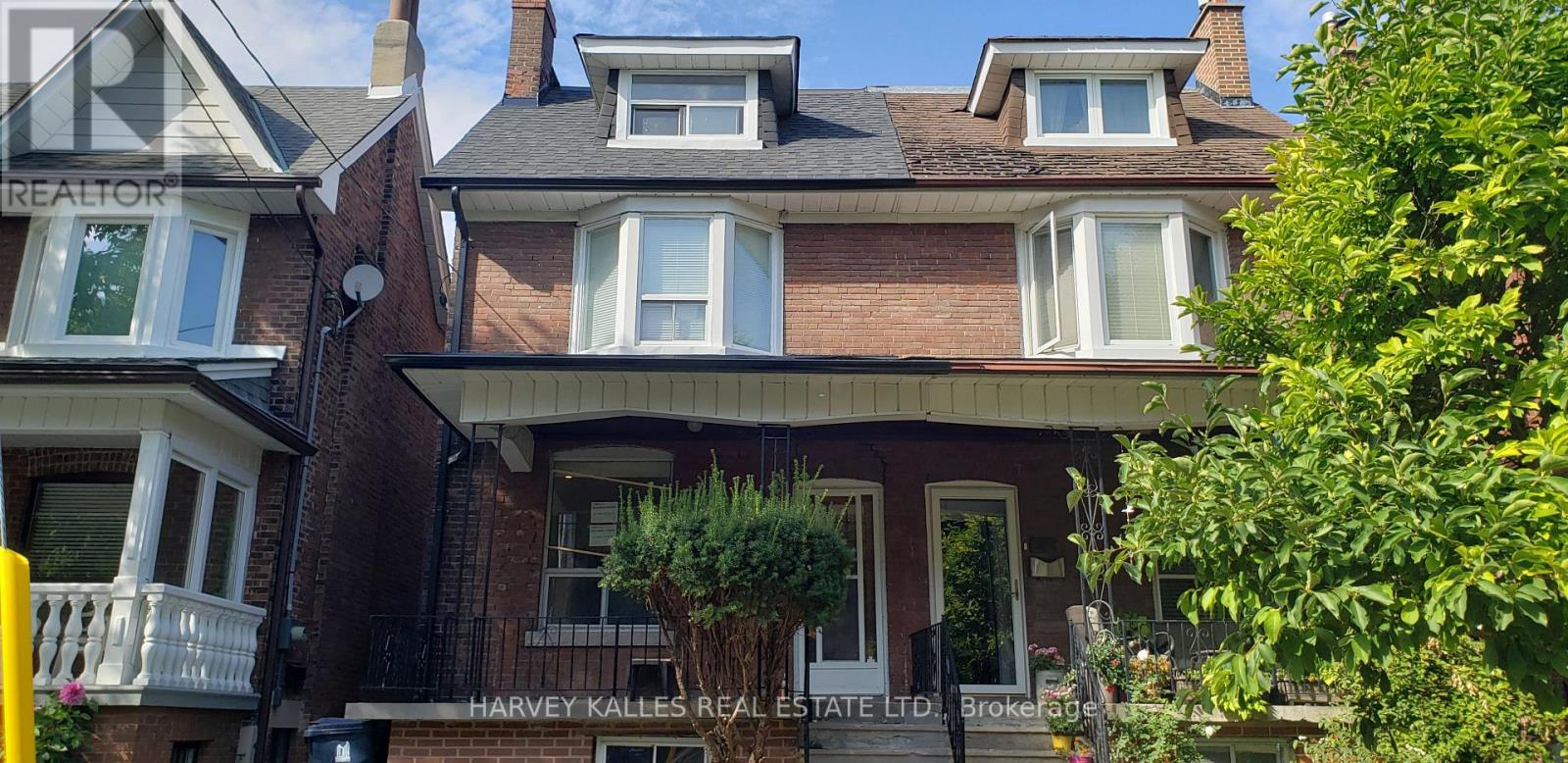 Red-brick two-storey house with bay windows, roof dormers, and a covered front porch.
