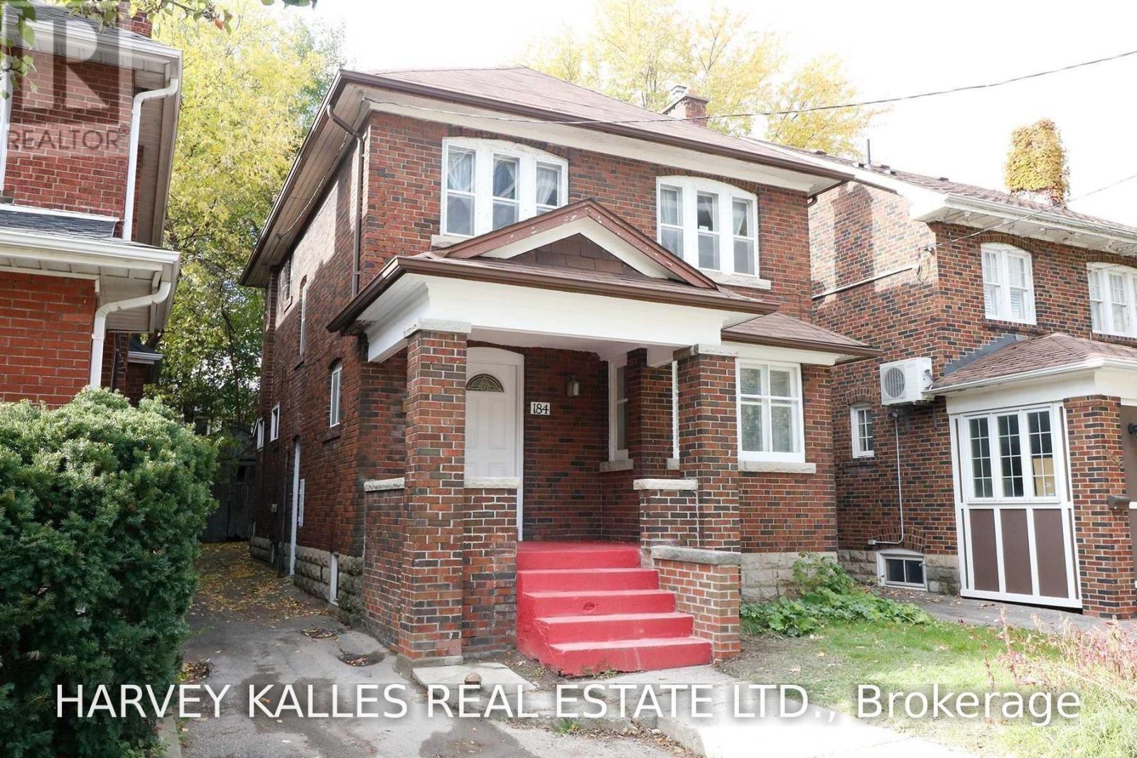 Two-storey red-brick house with a covered porch and bright red front steps.