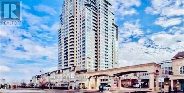 Residential condominium tower above street-level shops beneath a partly cloudy sky.