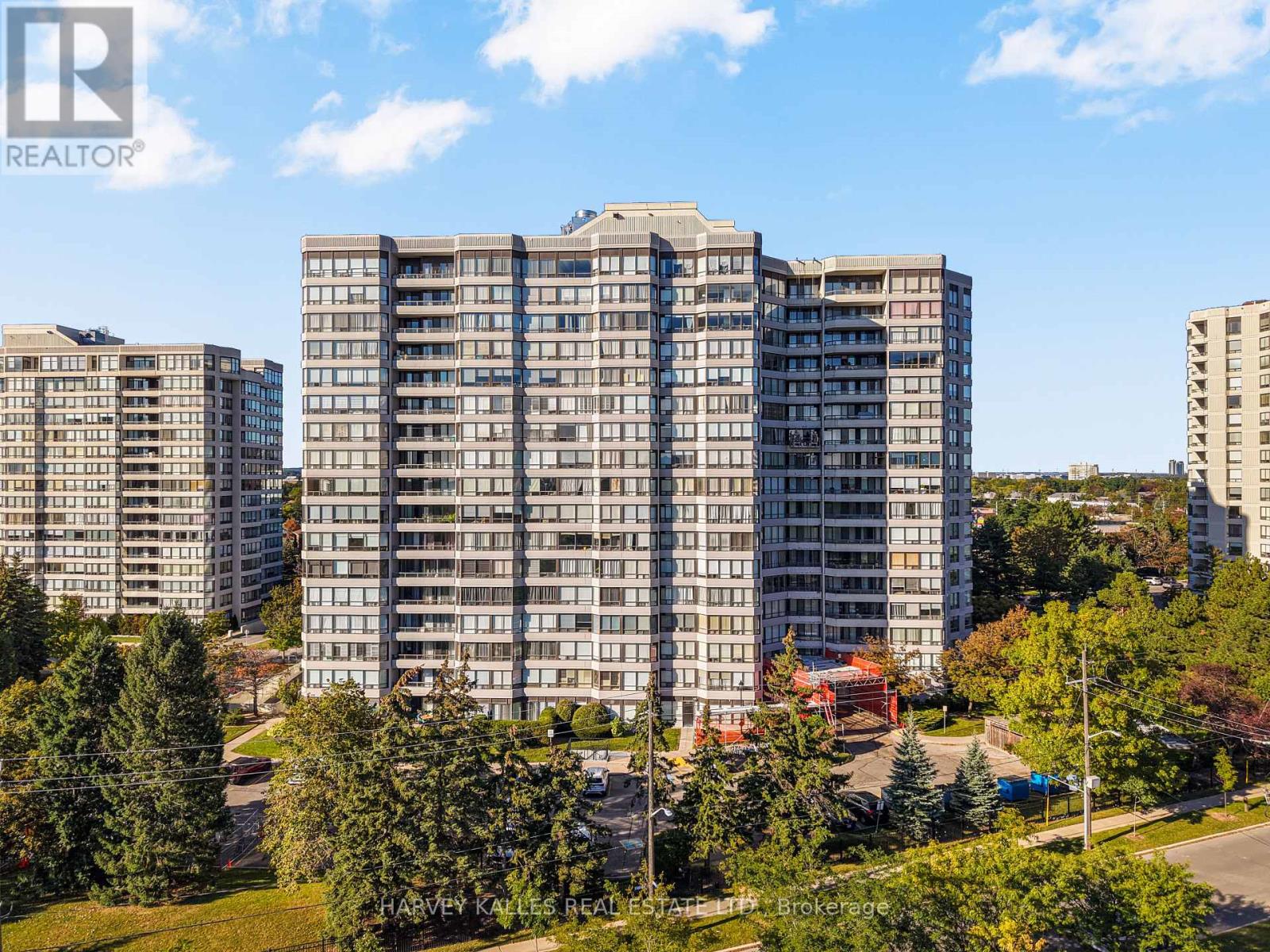 High-rise condominium complex with multiple beige towers set among autumn trees.