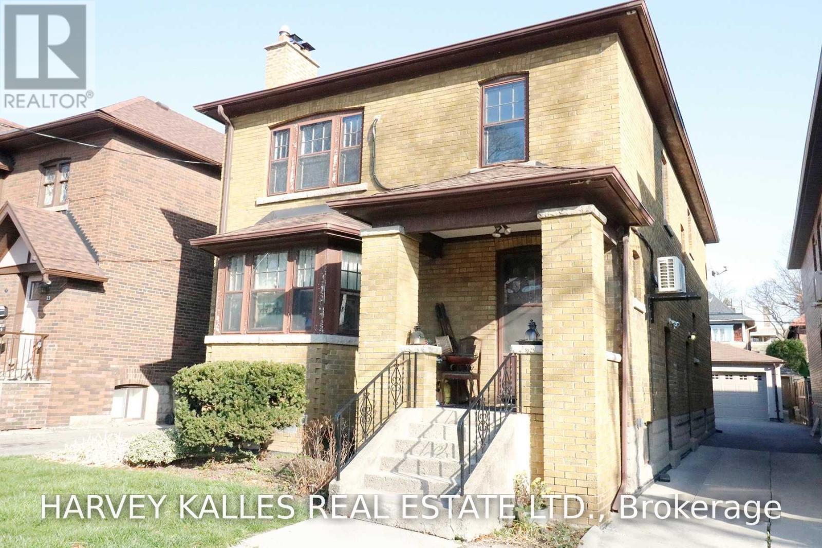 Two-story yellow-brick house with a covered porch, bay window, and driveway.