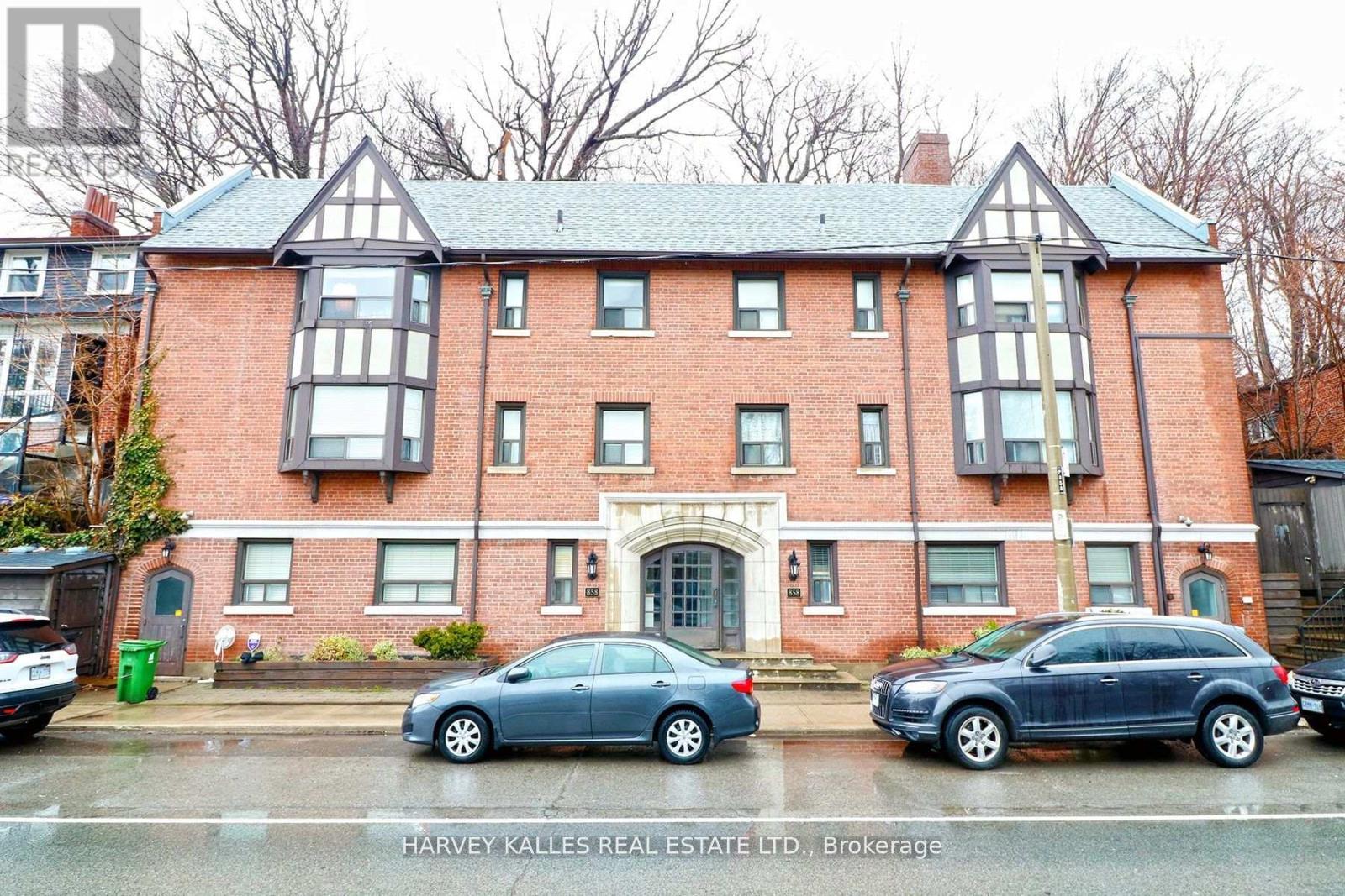 Red-brick residential building with paired bay windows, Tudor-style gables, and an arched entrance.
