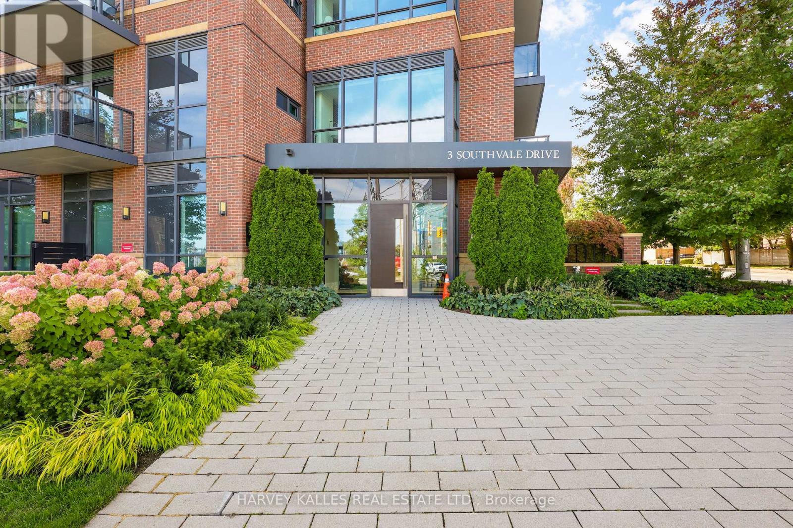 Condominium entrance at 3 Southvale Drive, with red-brick walls, glass balconies and landscaped flower beds.