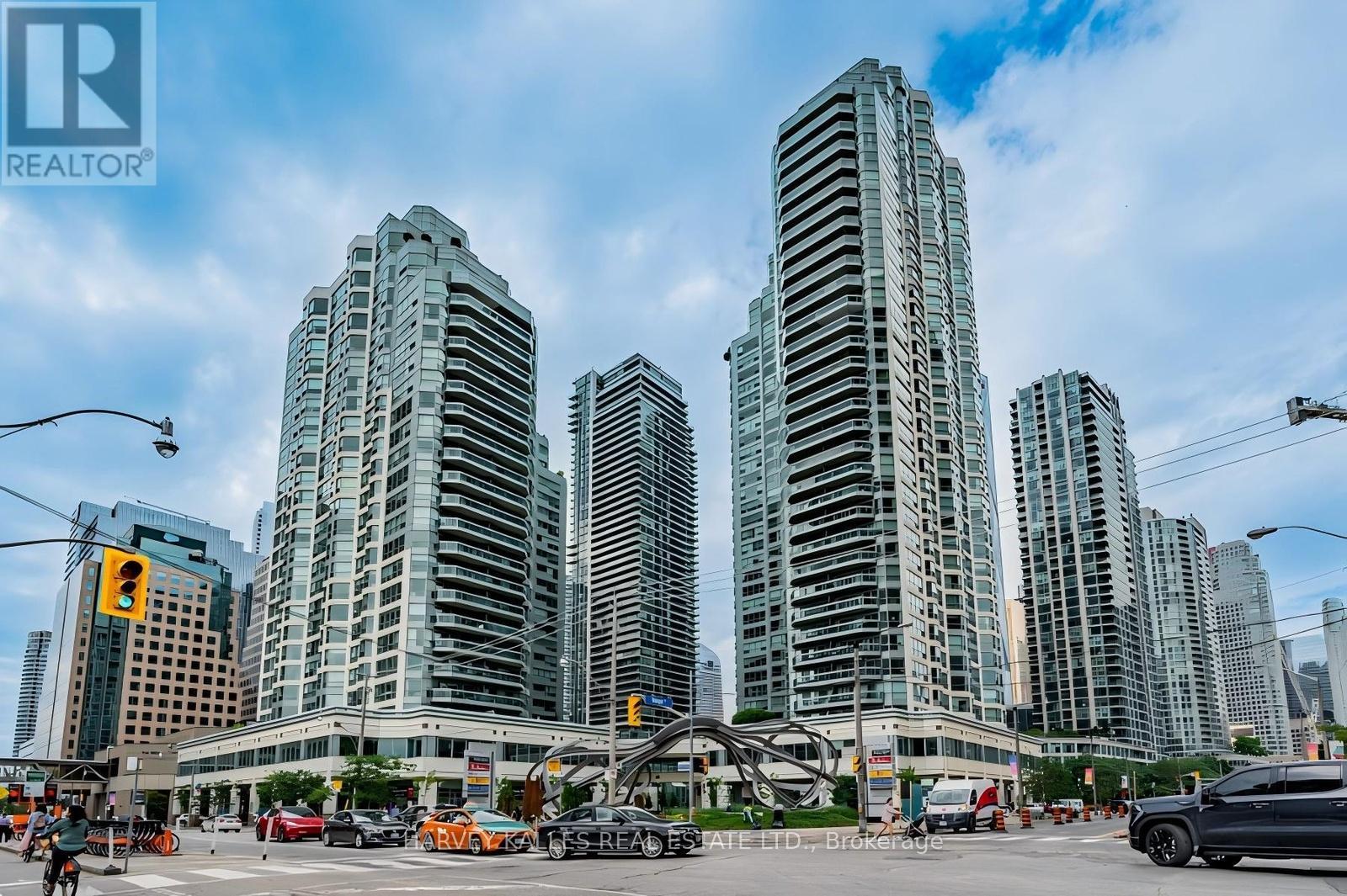 High-rise condominium towers above a busy city intersection with a large metal sculpture.