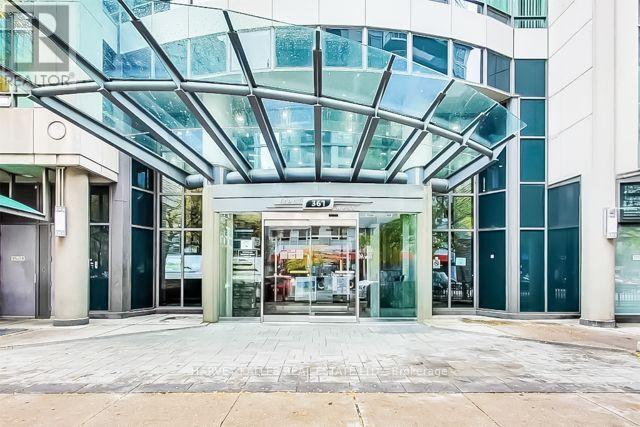 Modern building entrance with a curved glass canopy and the number 361 above the doors.