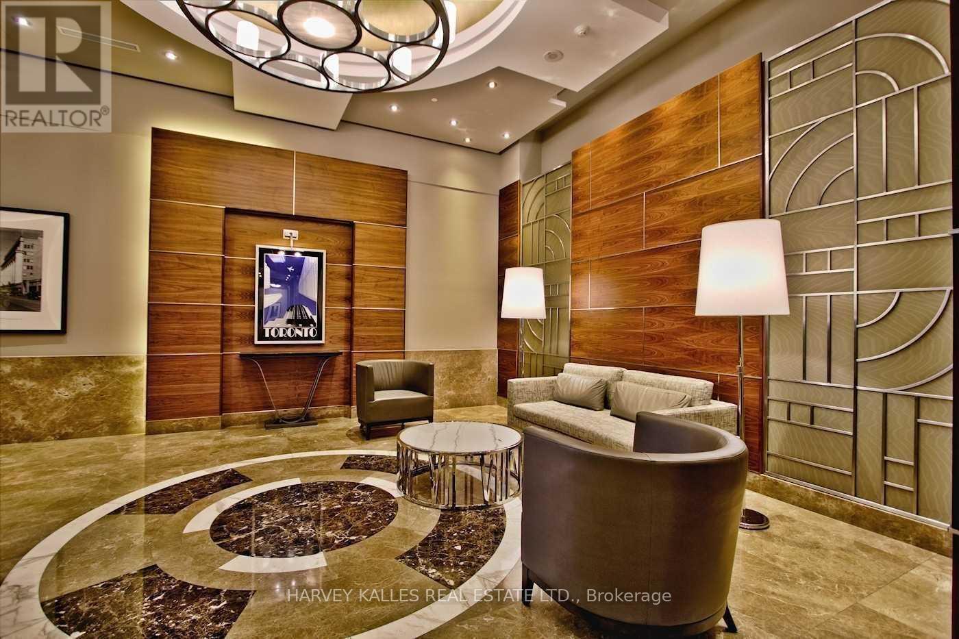 Condominium lobby with circular marble flooring, wood-paneled walls, and contemporary lounge seating.