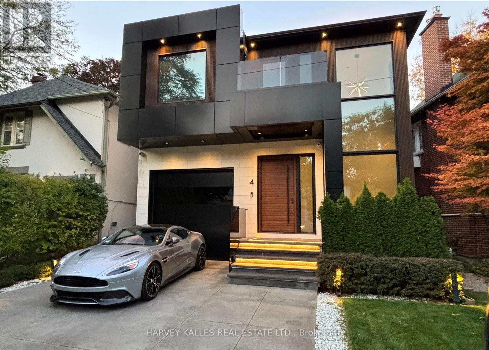 Modern Toronto home with charcoal cladding, illuminated entry steps, and a silver sports car in the driveway.