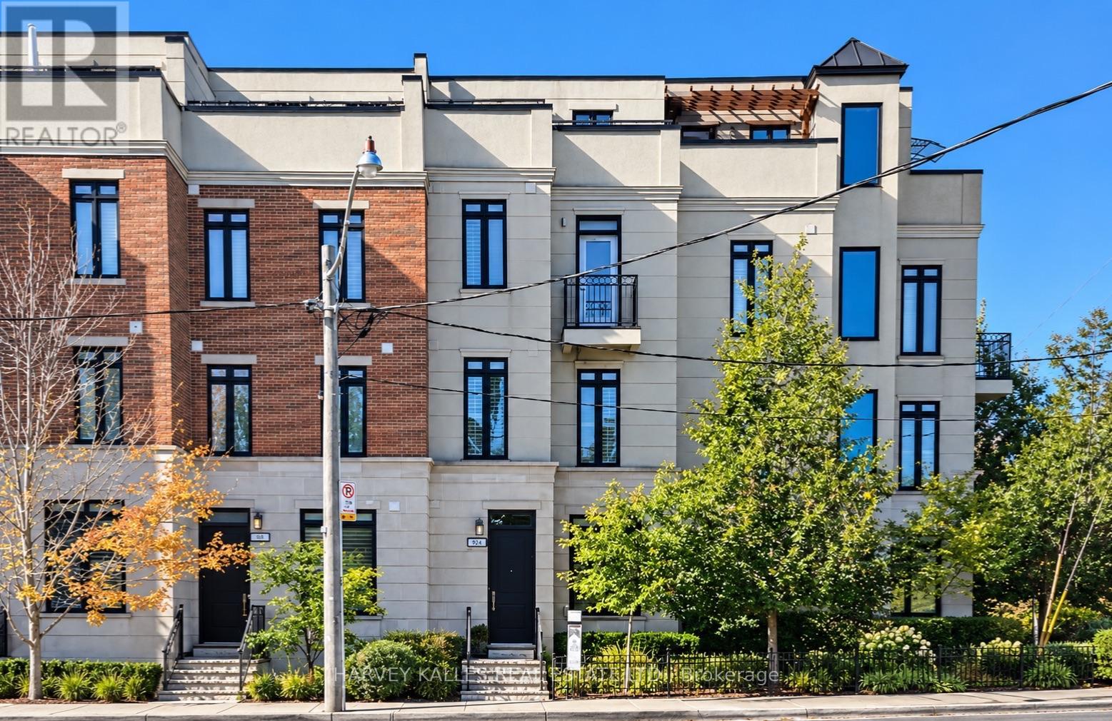 Modern townhouses with pale stone and red brick facades, balconies, and landscaped front gardens.